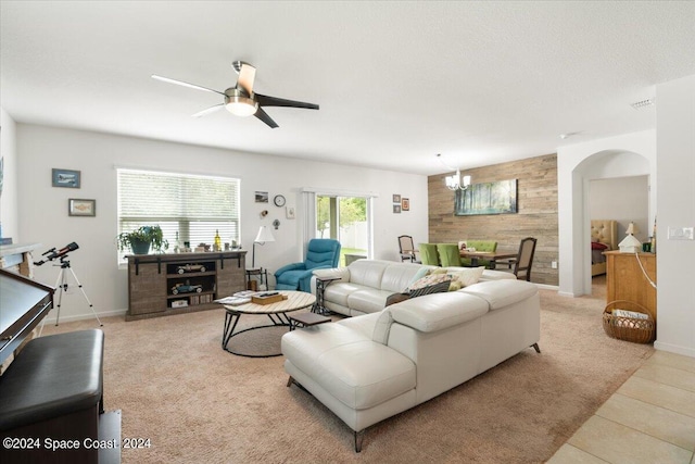 tiled living room with ceiling fan with notable chandelier