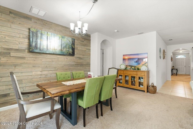 dining space featuring light colored carpet, wood walls, and a notable chandelier