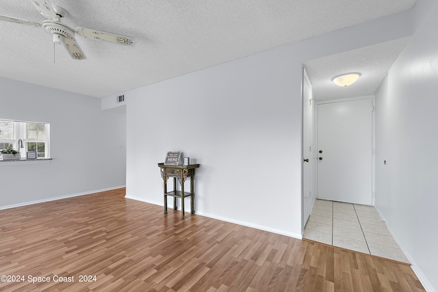 spare room with a textured ceiling, ceiling fan, and light hardwood / wood-style flooring