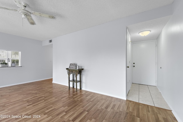 empty room with visible vents, a ceiling fan, a textured ceiling, wood finished floors, and baseboards