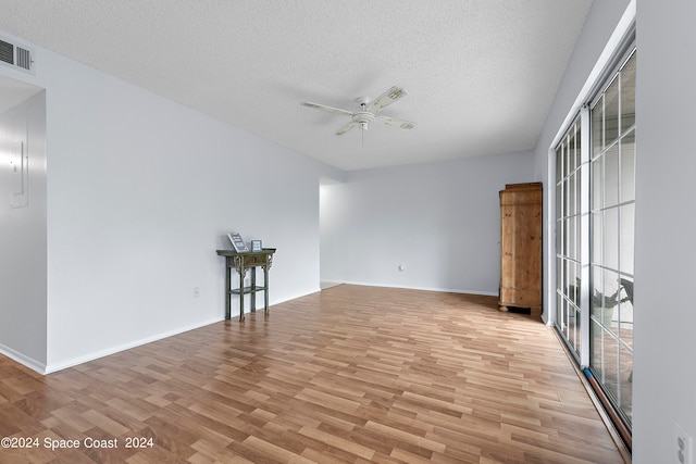 empty room with light wood-type flooring, a textured ceiling, and ceiling fan