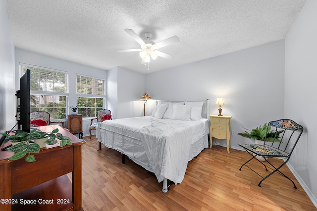 bedroom featuring ceiling fan, hardwood / wood-style floors, and a textured ceiling