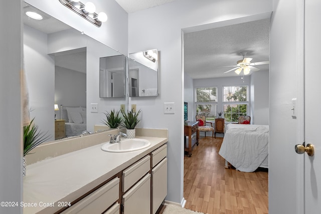 bathroom with a textured ceiling, vanity, hardwood / wood-style floors, and ceiling fan