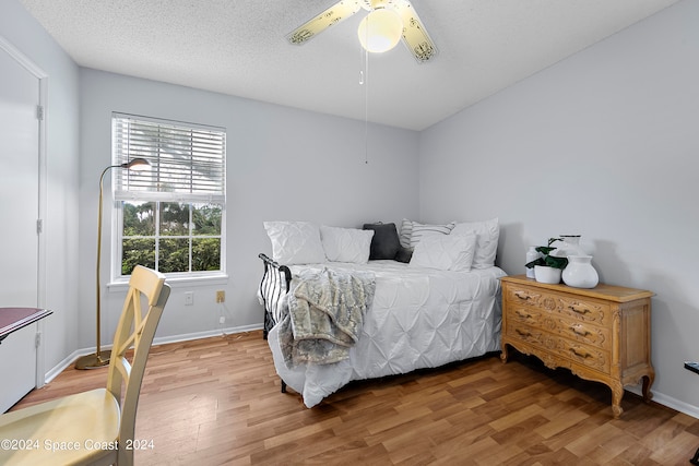 bedroom with ceiling fan, hardwood / wood-style flooring, and a textured ceiling