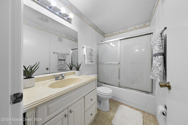 full bathroom with enclosed tub / shower combo, vanity, and toilet