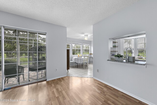 empty room featuring light hardwood / wood-style floors, ceiling fan, and a textured ceiling