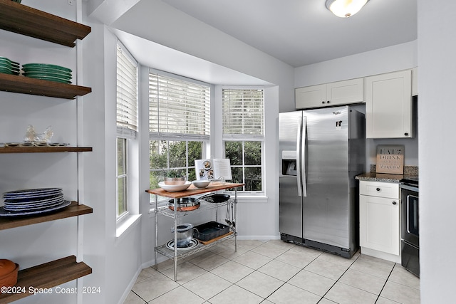 kitchen with dark stone counters, black range with electric stovetop, white cabinets, light tile patterned floors, and stainless steel fridge