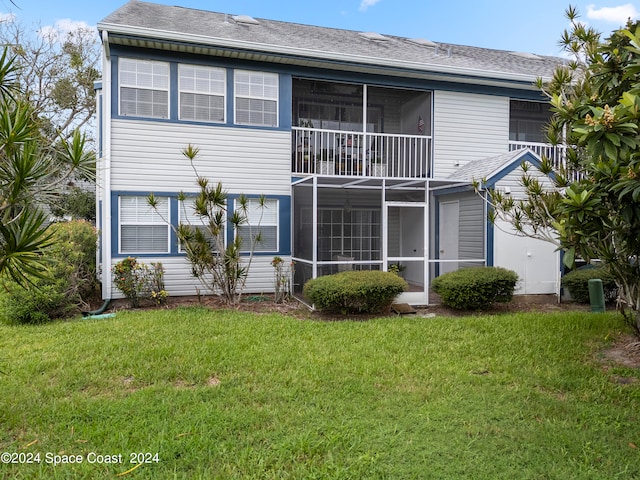 back of house with a balcony, a sunroom, and a yard