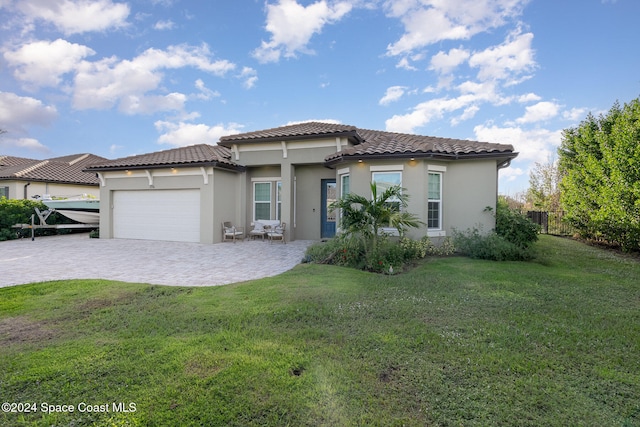 mediterranean / spanish house featuring a garage and a front yard