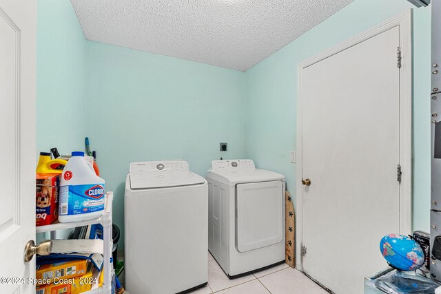 laundry area featuring light tile patterned floors, a textured ceiling, and washer and dryer