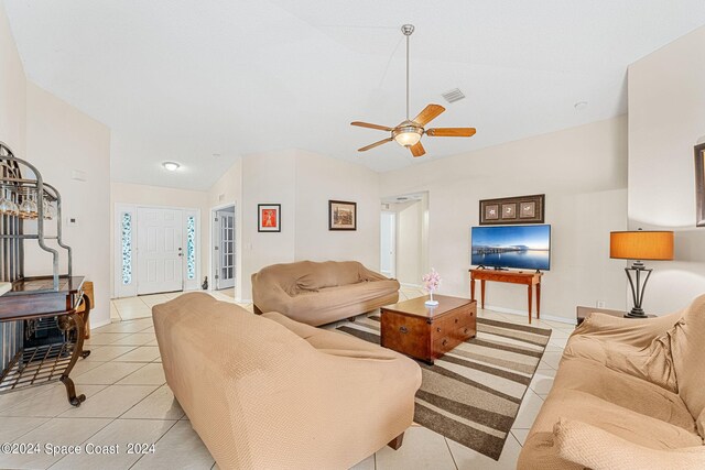 living room with lofted ceiling, light tile patterned floors, and ceiling fan