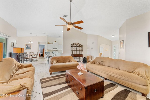 living room with a textured ceiling, high vaulted ceiling, light tile patterned floors, and ceiling fan