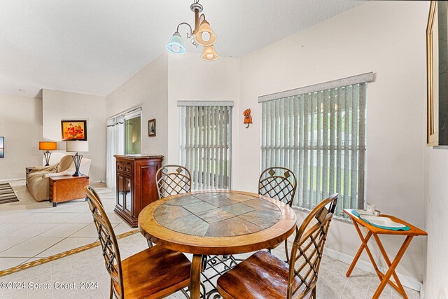 dining room with light tile patterned floors, a wealth of natural light, a notable chandelier, and a textured ceiling