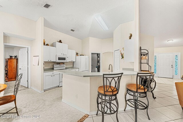 kitchen featuring white cabinets, white appliances, kitchen peninsula, and a textured ceiling