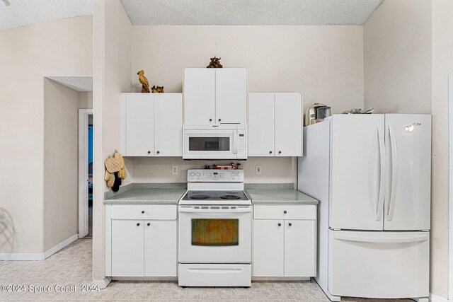 kitchen with white appliances, white cabinets, and a textured ceiling