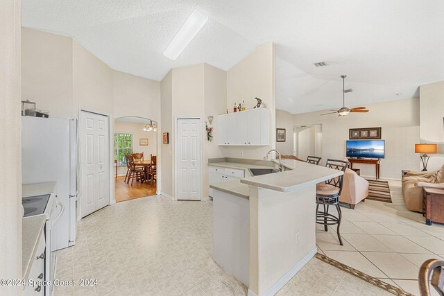 kitchen featuring white cabinetry, sink, electric range oven, ceiling fan, and a kitchen bar