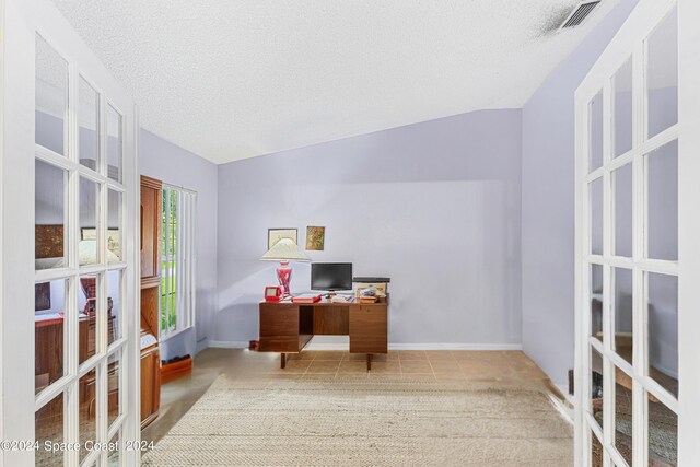 carpeted home office with french doors, lofted ceiling, and a textured ceiling