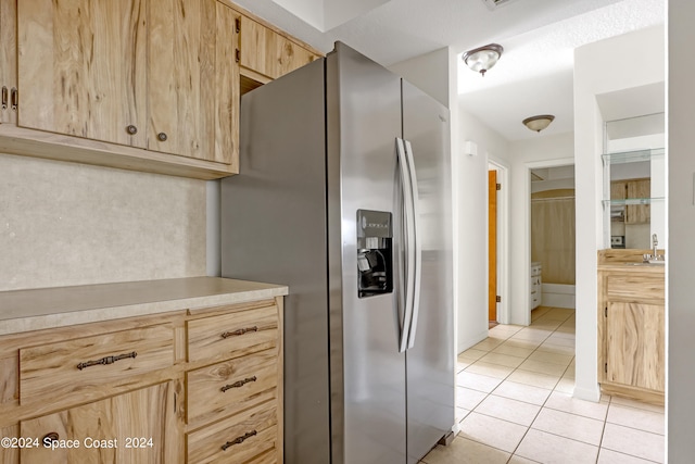 kitchen featuring light brown cabinetry, light tile patterned floors, stainless steel fridge with ice dispenser, and sink