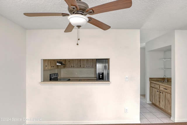 kitchen with a textured ceiling, ceiling fan, light tile patterned floors, and appliances with stainless steel finishes