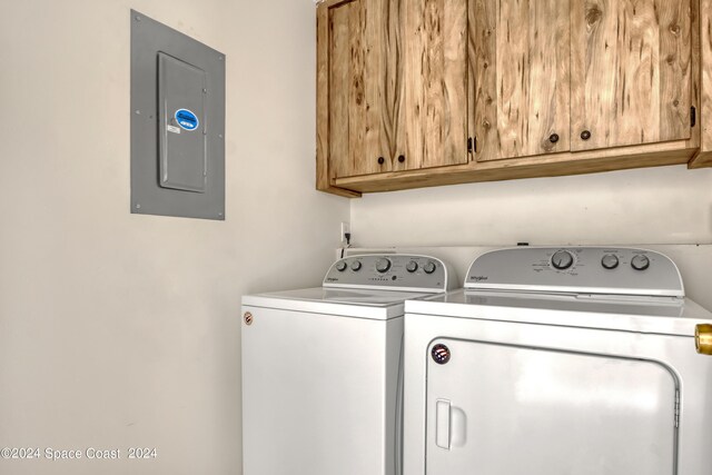 washroom with electric panel, cabinets, and separate washer and dryer