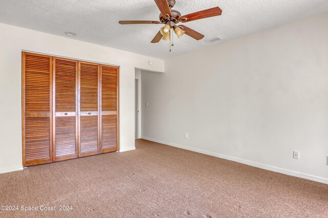 unfurnished bedroom featuring a textured ceiling, carpet flooring, ceiling fan, and a closet