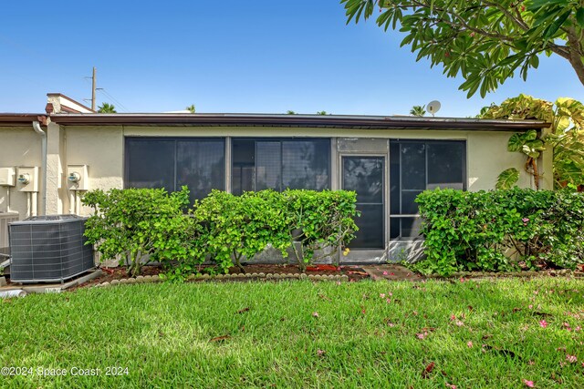 back of house featuring a lawn and central air condition unit