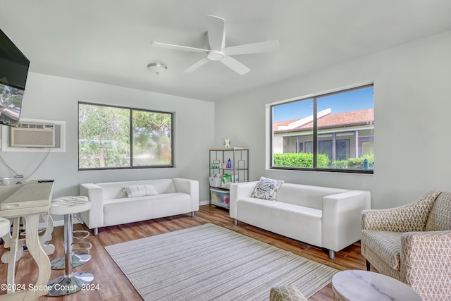 living room with a wall mounted air conditioner, wood-type flooring, and ceiling fan