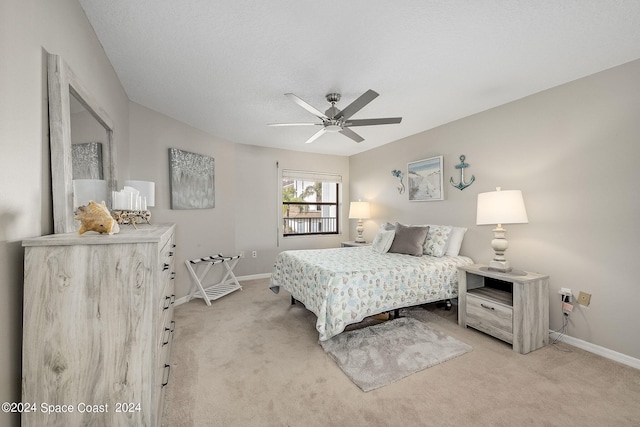 bedroom with light colored carpet, ceiling fan, and a textured ceiling