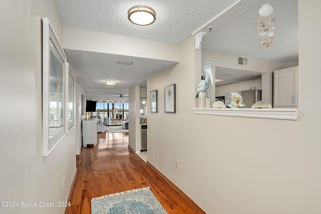 hallway with a textured ceiling and hardwood / wood-style flooring