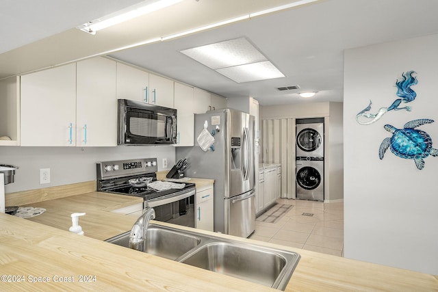 kitchen featuring white cabinets, appliances with stainless steel finishes, light tile patterned floors, and stacked washer and dryer