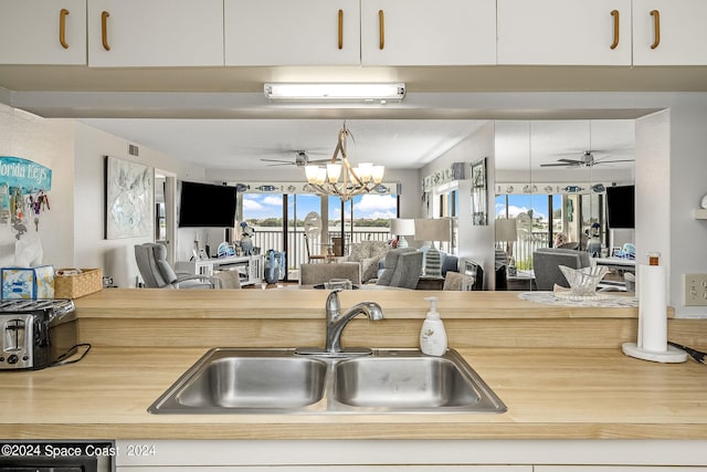 kitchen featuring ceiling fan with notable chandelier, white cabinetry, an AC wall unit, and sink