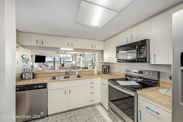 kitchen with white cabinetry, stainless steel appliances, an inviting chandelier, sink, and light tile patterned flooring