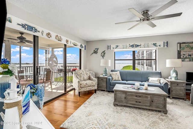 living room with a textured ceiling, plenty of natural light, ceiling fan, and hardwood / wood-style flooring