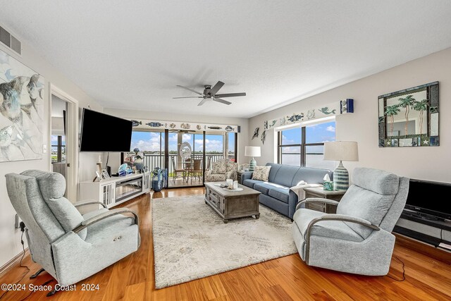 living room featuring a textured ceiling, wood-type flooring, and ceiling fan