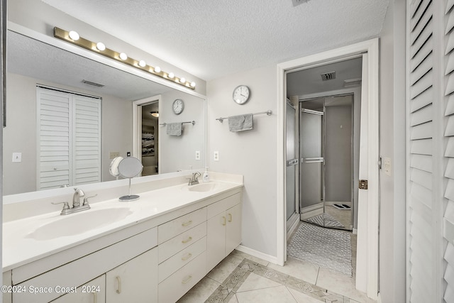 bathroom featuring a textured ceiling, vanity, an enclosed shower, and tile patterned flooring