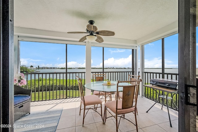 sunroom / solarium featuring a water view and ceiling fan