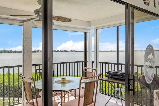 sunroom / solarium featuring ceiling fan and a water view