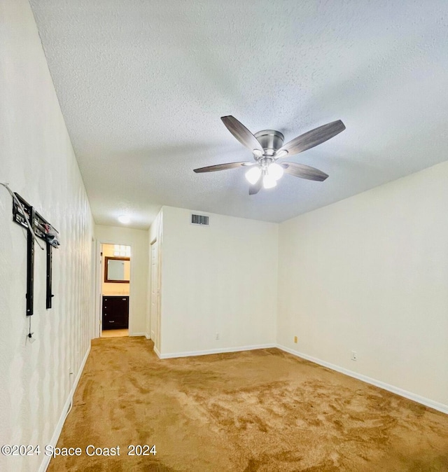 spare room featuring a textured ceiling, ceiling fan, and light carpet