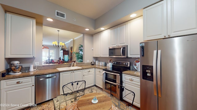 kitchen featuring dark stone countertops, a notable chandelier, stainless steel appliances, sink, and white cabinets