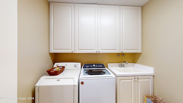 laundry room with washing machine and clothes dryer, cabinets, and sink