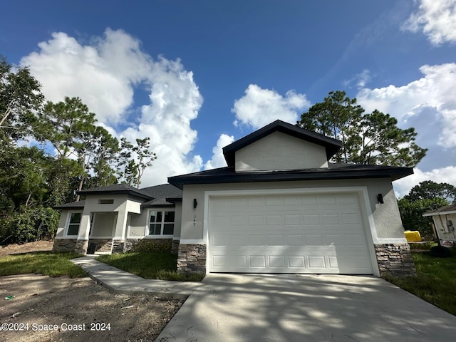 prairie-style home with stone siding, a garage, driveway, and stucco siding