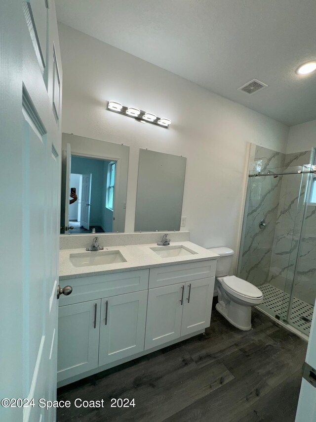 bathroom with a shower with shower door, hardwood / wood-style floors, toilet, and vanity