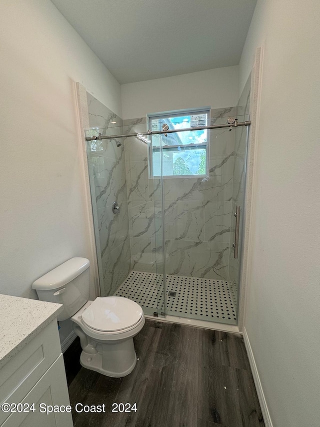 bathroom featuring a marble finish shower, toilet, vanity, and wood finished floors