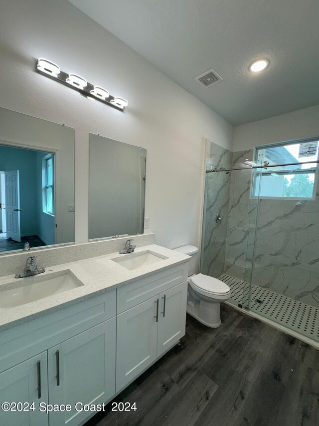 bathroom with hardwood / wood-style floors, vanity, toilet, and a shower with shower door