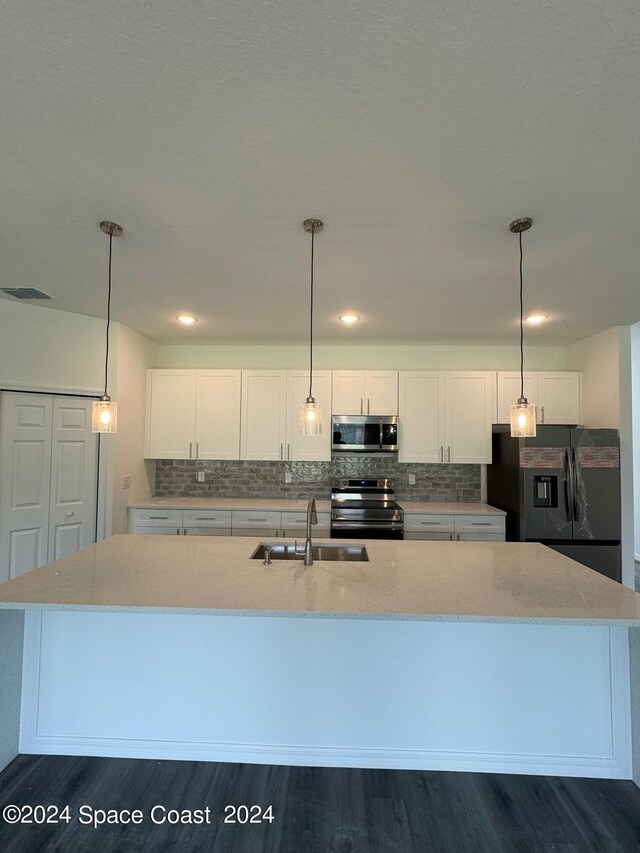 kitchen featuring white cabinetry, dark hardwood / wood-style flooring, sink, appliances with stainless steel finishes, and a center island with sink