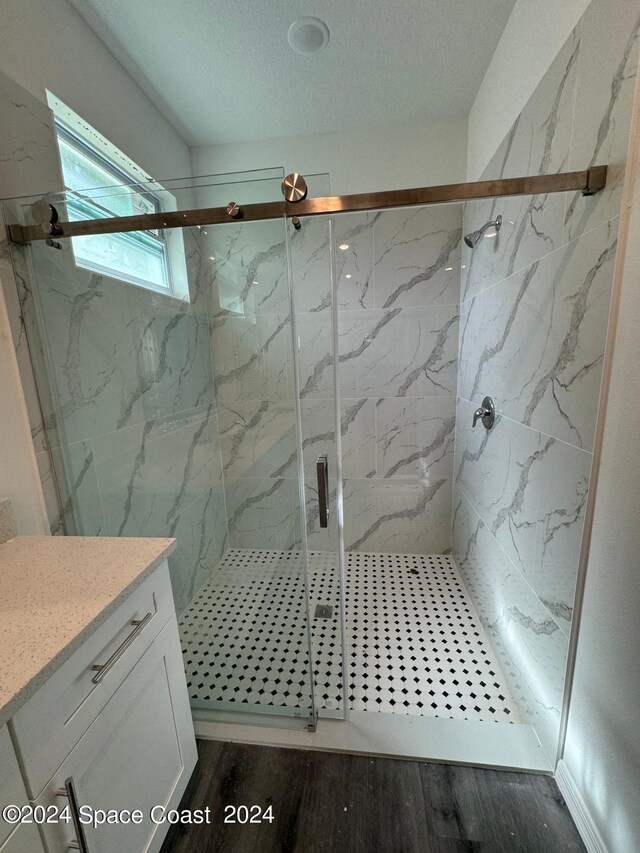 bathroom with a shower with door, hardwood / wood-style flooring, a textured ceiling, and vanity