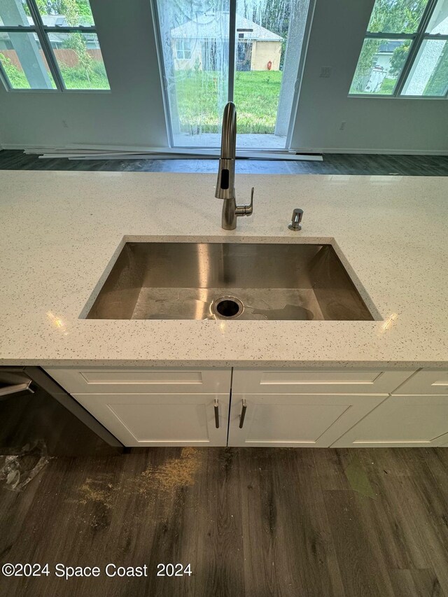 room details with a skylight, light stone counters, white cabinetry, sink, and dark wood-type flooring