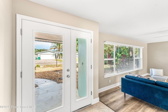 doorway with a wealth of natural light, light hardwood / wood-style flooring, ceiling fan, and french doors