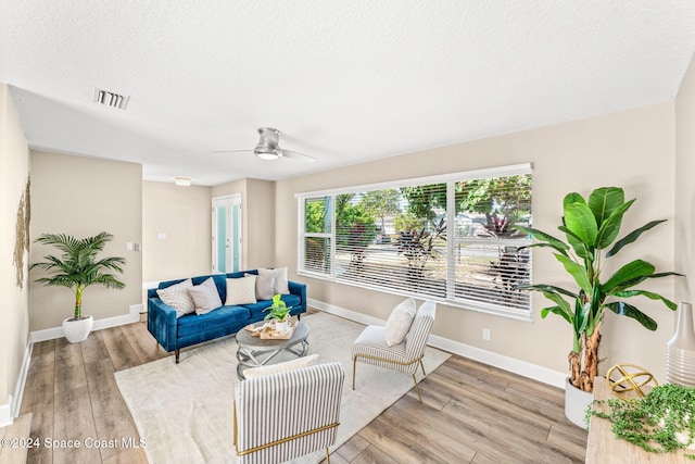 living room featuring ceiling fan, a textured ceiling, and hardwood / wood-style flooring