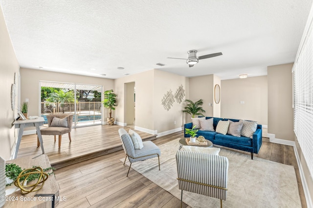 living room featuring a textured ceiling, light hardwood / wood-style flooring, and ceiling fan